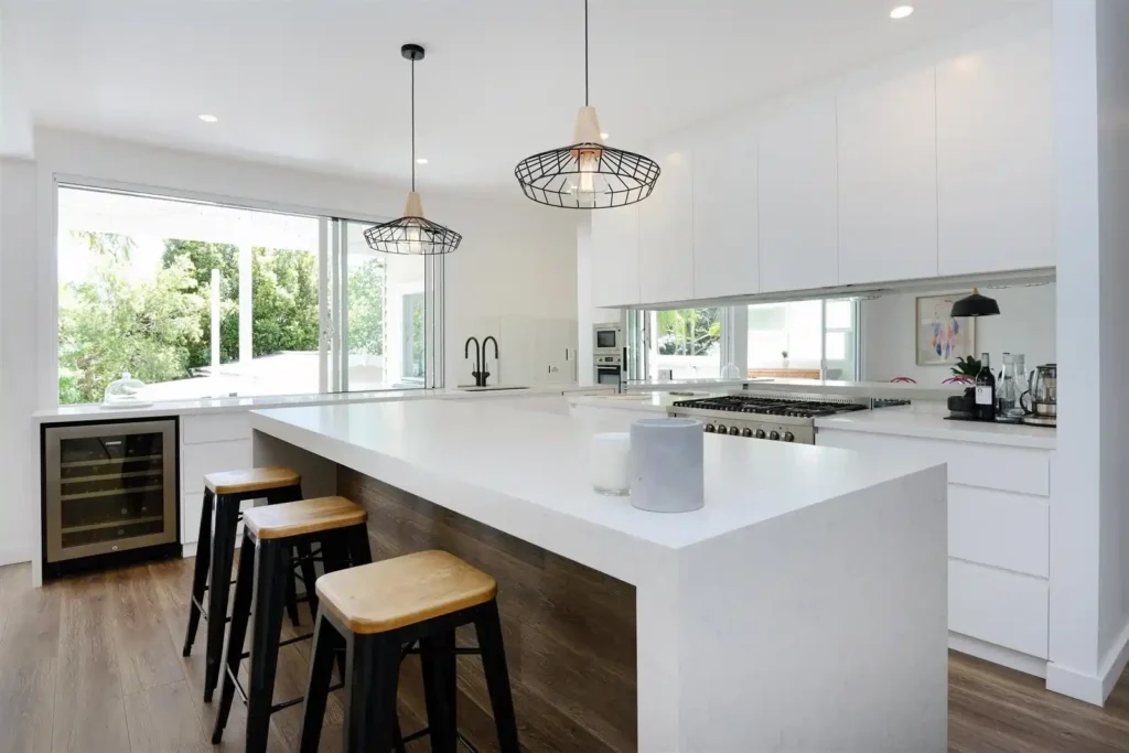 Modern open-plan kitchen renovation in Melbourne featuring custom white cabinetry and stone island bench by Destin Constructions.